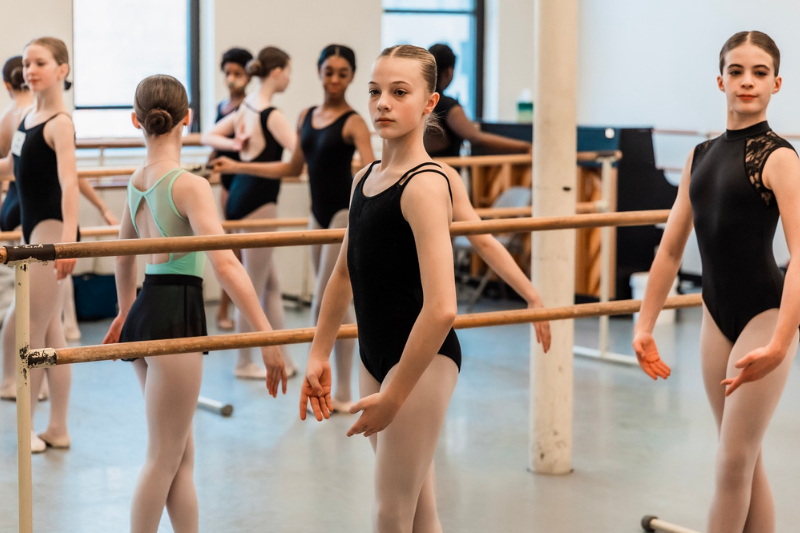 Group of young dancers in ballet class, at the barre
