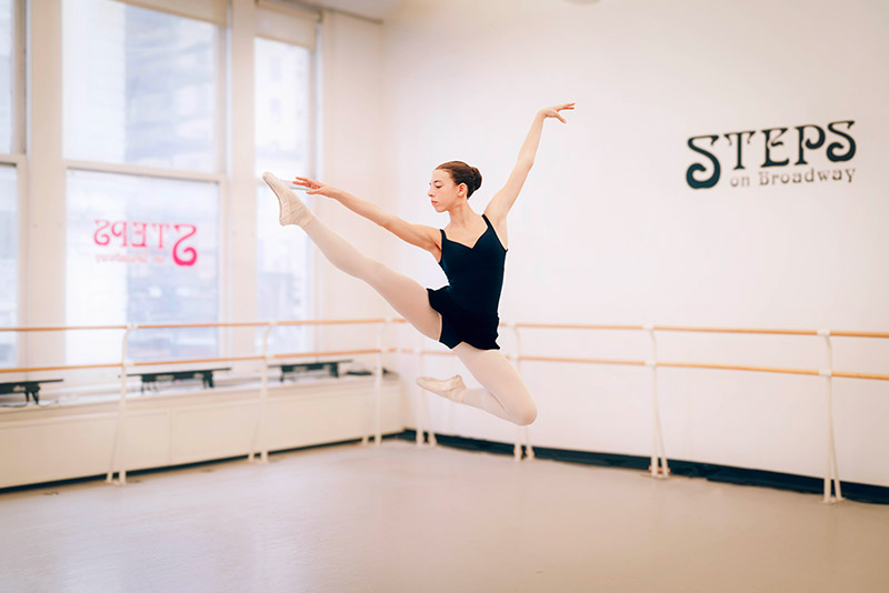Make Steps a part of your success story - a ballet dancer leaping successfully across a  dance studio at Steps