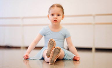 first steps seated young dancer staring into the camea with only her toes in focus